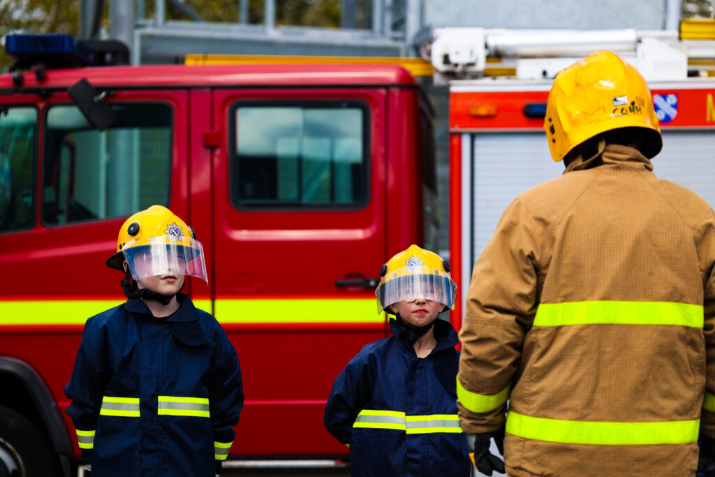 Two young people standing in line wearing fire safety clothing with Fire Officer 